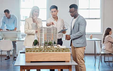 不同的建筑师或项目经理讨论建筑扩建的平面图 亚洲工程师向白人和非裔美国客户展示新办公室的蓝图和 3D 模型图片