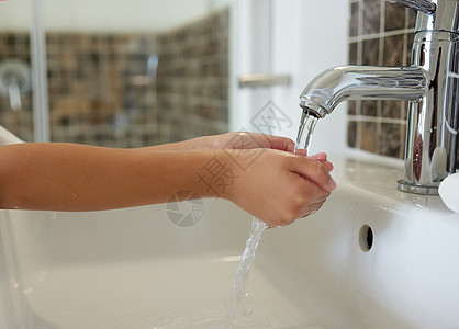一个孩子在浴室的水槽旁用自来水洗手的特写镜头 一个孩子通过清洁手指来预防病毒 从而练习卫生和清洁图片