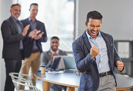 不要选择保持不变 一位年轻的商务人士在他的同事面前庆祝胜利 他的同事在后台开会背景图片