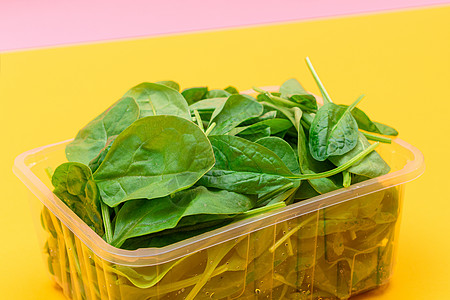 黄色背景透明塑料套件中新鲜的婴儿菠菜叶新片食物减肥排毒绿叶蔬菜活食绿色沙拉草本植物树叶图片