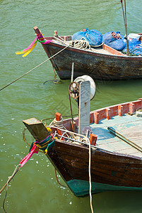 Wooden渔船在渔获返回后沿海漂流海洋木头蓝色运输工具绳索海岸旗帜支撑港口图片