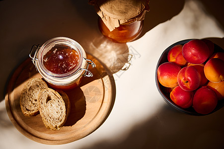 木板上自制果酱和全食面包的顶端景象 桌子上的蓝瓷碗中成熟的红杏子图片