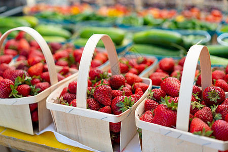 在蔬菜市场上出售的草莓 木篮中的生多汁草莓与背景中的其他水果和浆果一起陈列在市场上农场场所零售杂货商店铺农业园艺甜点生产收成图片