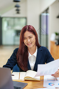 使用计算机和预算文件在办公桌上使用的亚洲女性工人人数员工中年人成人投资阅读文档工作金融电脑商务图片