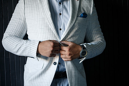 时尚新郎在夹克上扣纽扣人士男性按钮阴影手指男人服装衣服蓝色领带图片