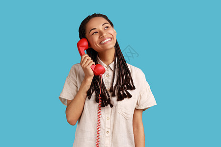 微笑的女人拿着红色的旧电话 在手边 看不着梦幻般的面部表情图片