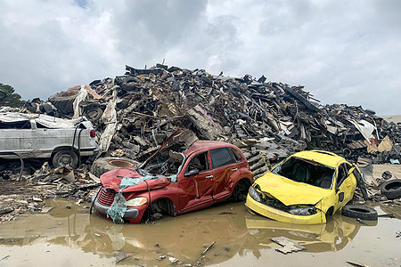 垃圾场的破车 汽车废料 被压碎的腐蚀旧汽车堆放在废品场的水坑里图片