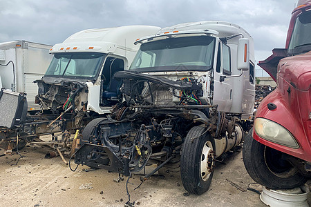 事故发生后垃圾场的三辆破卡车 发动机坠毁的废弃打捞车 有汽车残骸碎片的室外公园图片