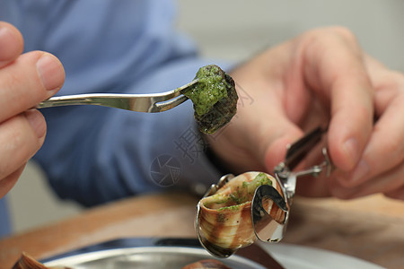 男人用特别的叉子和蜗牛叉来吃布哥根咖啡饼烹饪绿色食物昆虫美食餐厅草本植物蜗牛黄油动物图片