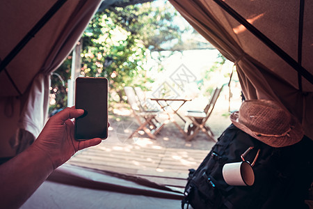 一家人野营在露营帐篷里拿着电话的人的手背包家庭风景手臂视角树木娱乐冒险男性闲暇背景
