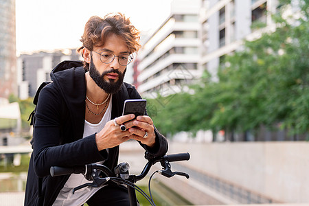 坐在车上男人用手机打字 坐在他的自行车上背景
