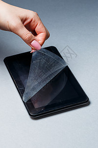 黑色刮黑平板板 灰色背景上有保护胶片 保护您的设备屏幕磨炼电话裂缝男人药片塑料女孩事故玻璃展示图片