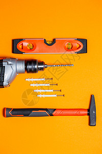 维修工具 橙色背景墙上的钉锤 钻头 销钉 向导工具包插头材料控制板压板建造角落塑料金属底座锤子图片