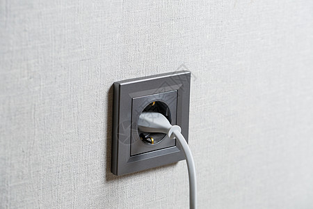 墙壁上的灰色出口 包括一个带有白线的装置 从电源出口充电适配器金属绳索电压电气插头充电器活力女性连接器图片