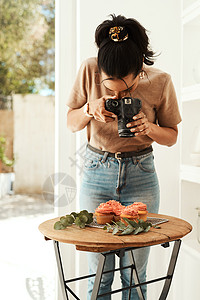 一位有吸引力的年轻女商务人士站着 用她的相机为博客拍摄纸杯蛋糕照片 在部落格上图片
