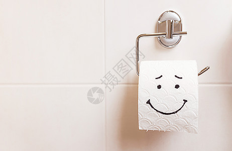 一卷手纸 面带快乐的脸庞 挂在浴室的白墙上疼痛笑脸疾病卫生纸肠子压力缓冲器病痛卫生卷纸组织图片