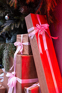 在圣诞树和冷杉制成的墙附近的街道上制作礼品盒 红色霓虹灯照耀着盒子 圣诞节和新年的概念 12 月 25 日图片