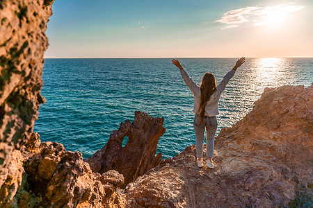 女游人 举手而立 天涯海角 见龙岩 女孩欢迎太阳 概念设计 一个成功的女人张开双臂看着夕阳海岸假期火山海岸线蓝色悬崖旅行全景石头图片