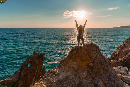 女游人 举手而立 天涯海角 见龙岩 女孩欢迎太阳 概念设计 一个成功的女人张开双臂看着夕阳时段动物火山海岸线全景假期旅游黄金地标图片