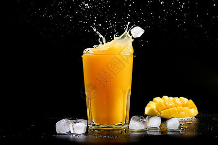 新鲜芒果汁 黑背景上喷出芒果鸡尾酒 冰块落到芒果汁中背景图片