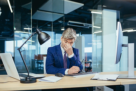一名经验丰富的灰发商务人士在计算机工作到很晚 疲劳累员工商业办公室瞌睡桌子损失挫折管理人员经理职业图片