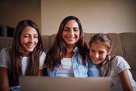 他们是三个同类 一位迷人的母亲和她的两个女儿在家里用笔记本电脑看电影图片