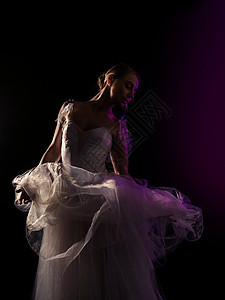 优雅的芭蕾舞演员穿着白色芭蕾舞短裙 在黑暗中用霓虹灯和黑色背景上的烟雾跳舞古典或现代芭蕾舞元素 艺术概念图片
