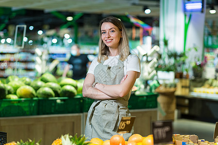 一个蔬菜区超市的年轻女性工匠 站着微笑 手举过身来图片