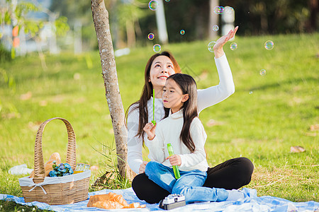 在野餐期间玩得开心 吹肥皂泡泡泡喜悦父母花园童年太阳女孩公园乐趣女士女儿图片