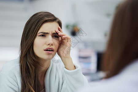 昨晚发生了什么 白天在家里 一个看起来很困惑的年轻女人看着镜子 用手抚摸着自己的脸图片