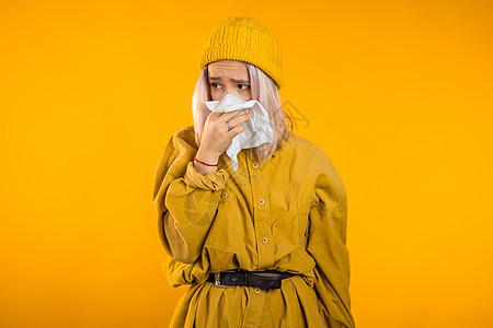 年轻女孩对着纸巾打喷嚏 隔离在黄色女人身上的是生病 鼻塞或流鼻涕和发烧 冠状病毒 2020 年流行病 疾病概念药品女性家庭组织鼻闻高清图片素材