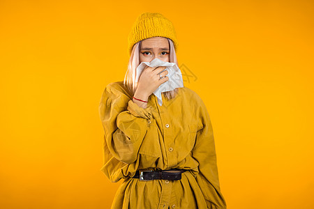 年轻女孩对着纸巾打喷嚏 隔离在黄色女人身上的是生病 鼻塞或流鼻涕和发烧 冠状病毒 2020 年流行病 疾病概念流感成人症状客厅女吹高清图片素材