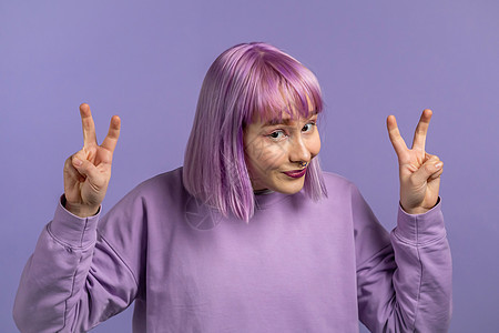 漂亮的女人染着紫色的头发 用手和两个手指展示空气引用手势 弯曲的手指在紫色背景下被隔离 不好笑 讽刺和讽刺的概念图片