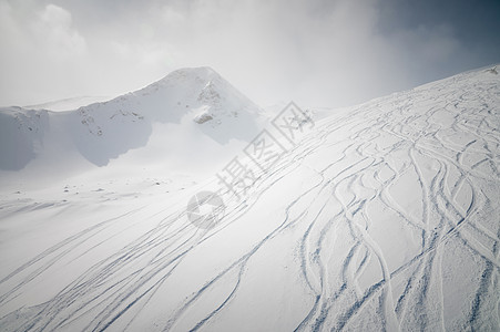 在阳光明媚的冬季日子里 有滑雪和雪板足迹的冰雪山坡 在高山上自由航行穷乡天空小路山脉粉末季节白色旅游僻壤旅行图片