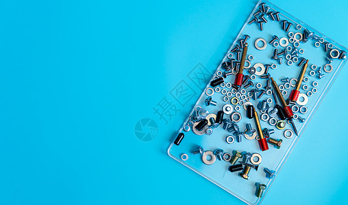 蓝色背景塑料托盘中的金属螺栓 螺母 垫圈和螺钉的顶视图 紧固件设备 机械技术人员的硬件工具 螺纹紧固件配件 五金螺母和螺栓图片