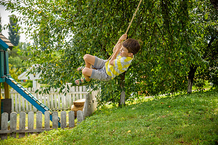 快乐的小男孩在城外休息时发现的秋千上玩得很开心 与孩子们一起度过积极的休闲时光享受闲暇男性孩子幸福公园运动童年冒险森林图片