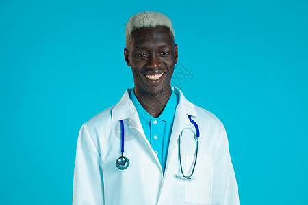 身穿专业医疗大衣 面带微笑的非洲医生的肖像 Doc man在蓝色背景中被孤立图片