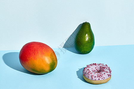 新鲜水果和甜食 甜甜圈芒果和两色背景的鳄梨背景图片