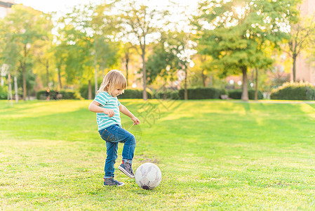 小男孩在公园的草地上玩球图片