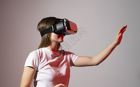 在工作室探索人工计算机世界或在霓虹灯下玩电子游戏的虚拟现实体验中 戴着 VR 耳机的黑发年轻女性兴奋地触摸着空气女孩视频技术女士图片