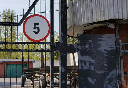 限速5公里由警卫守卫的工业车库停车场区入口处 四周围有钢栅栏 大门上有一个标志 将速度限制在5公里以内背景