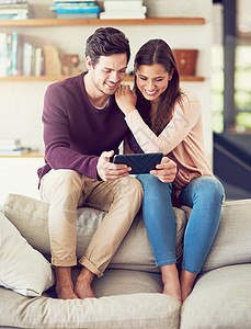 在小屏幕上看电影也不算太糟糕 一个快乐的年轻夫妇使用数字平板电脑 在家沙发上放松一下图片