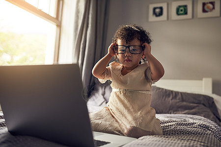 床上电脑一个可爱的小女孩坐在床上时 使用笔记本电脑的全长肖像画 (笑声) (掌声)背景