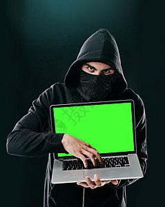 你的个人信息现在是我的了 站在黑暗背景下使用笔记本电脑的计算机黑客的肖像图片