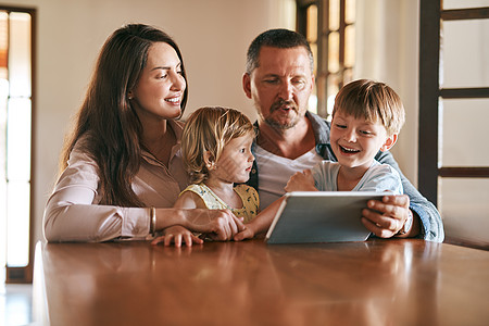 科技在现代家庭占有一席之地 四口之家的年轻人在家里一起使用数字平板电脑图片
