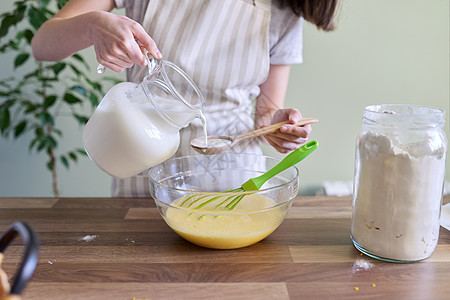 烤橙煎饼 将牛奶倒进碗中的女性手的近距离准备橘子煎饼 奶粉加到碗里图片