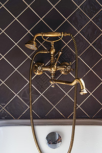 金水龙头和棕色瓷砖背景的古董式淋浴图片