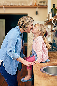 他们全心全意地爱着对方 一位开朗的年轻母亲在家里的厨房里和她年幼的小女儿碰鼻子图片