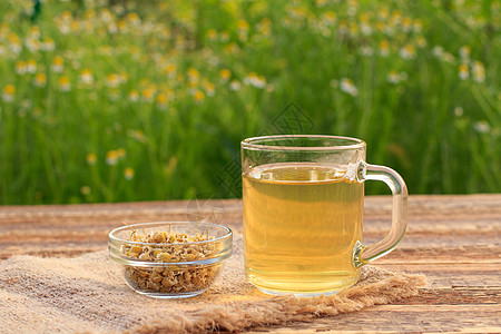 一杯绿色茶和干白色甘菊花 在户外的玻璃碗里洋甘菊药品饮食早餐母菊食物草本植物植物杯子图片