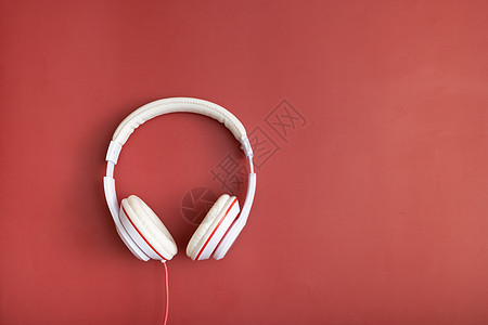 红色背景的白色耳机 最小时尚音乐概念 复制空间 顶视图 平面图片